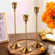 Bougeoirs cuivrés de trois hauteurs sur une table