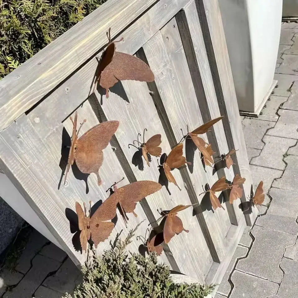 Papillons muraux en métal finition rouille disposés sur une clôture